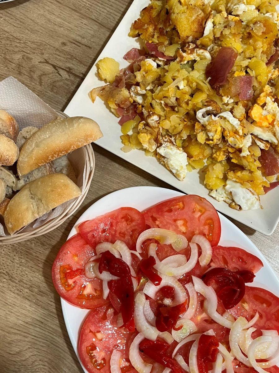 Huevos rotos con jamón, ensalada de tomate con cebolla y pan, en Bar El Aguilucho.